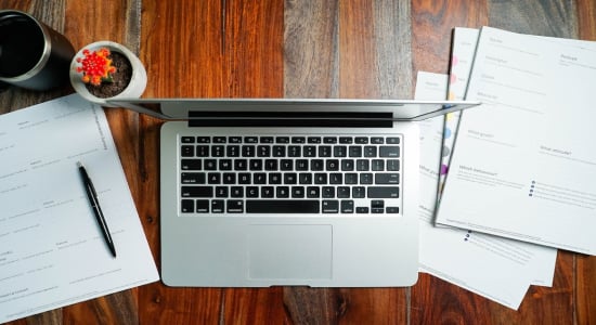 Laptop on desktop with cybersecurity resources around it